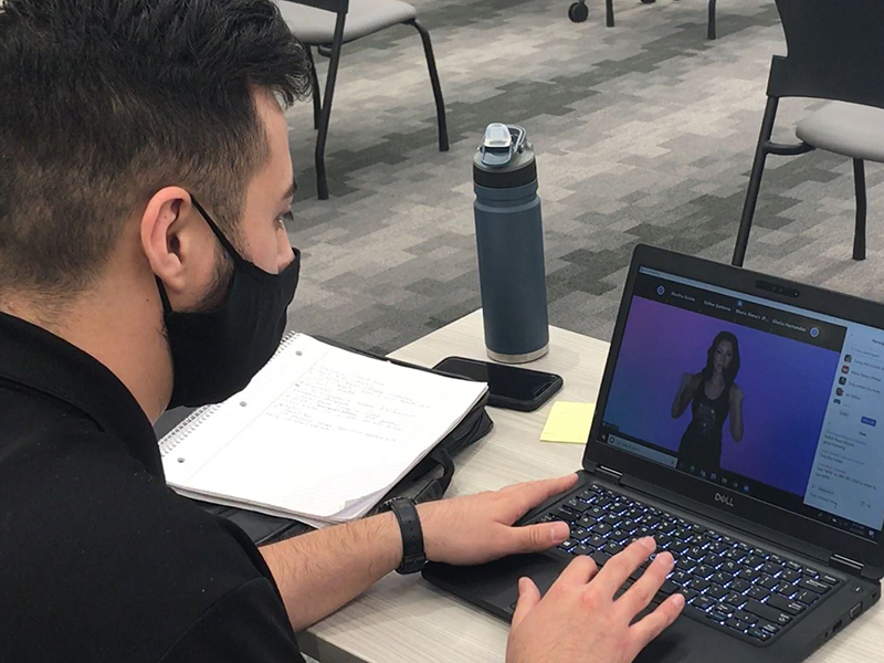 Man wearing a covid mask and attending a virtual meeting