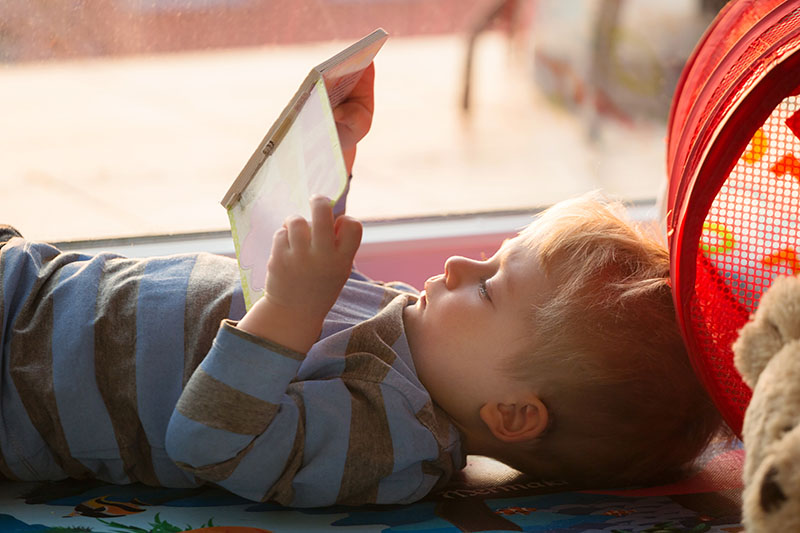 Young boy laying on his back reading