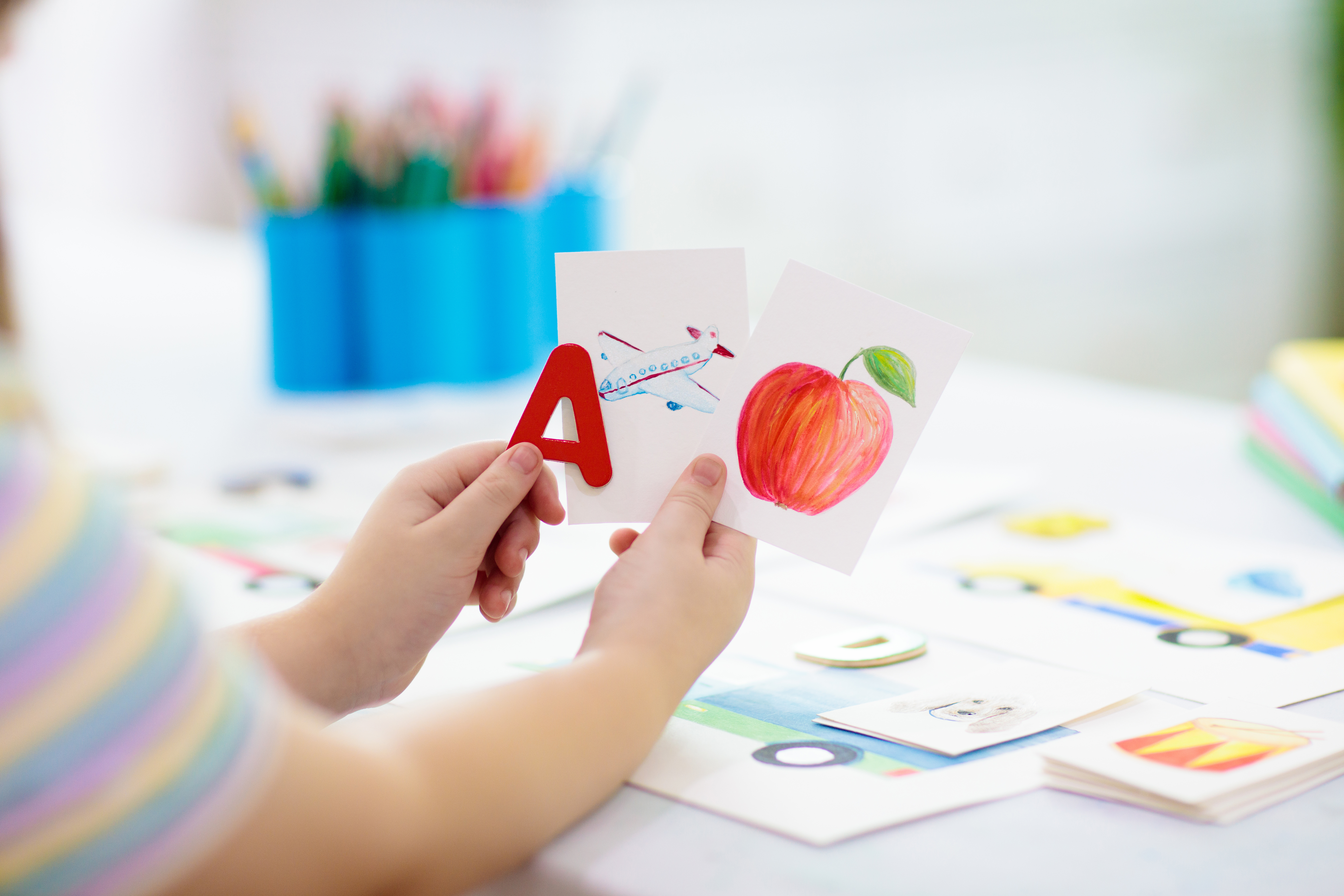 Child holding up letters and flashcards